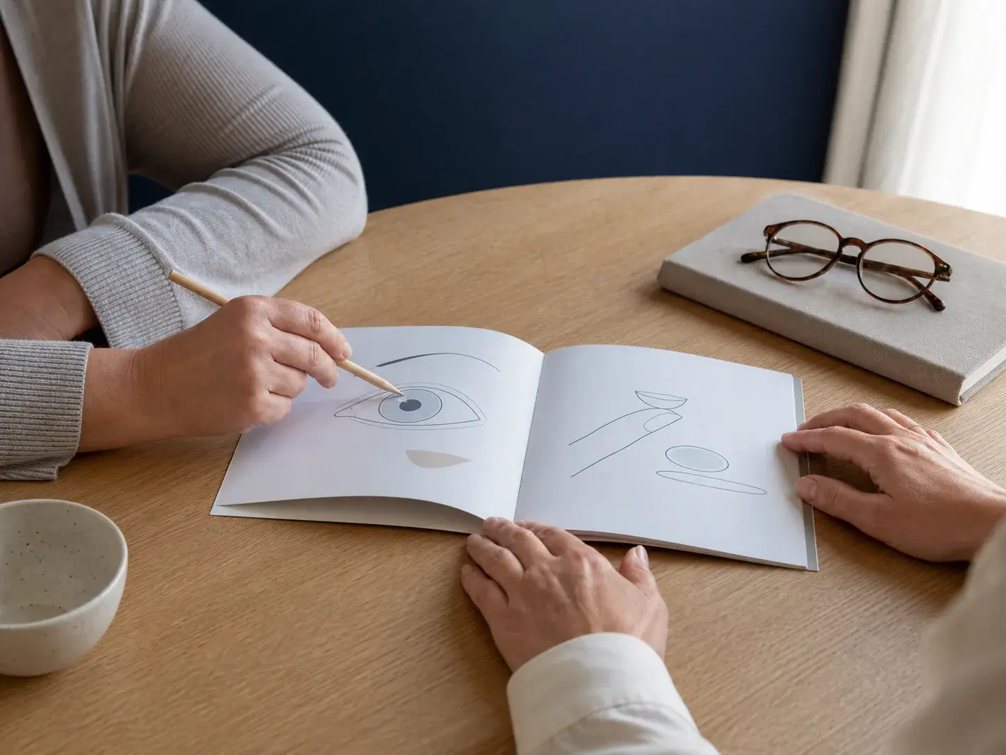 Two adults reviewing a simple unbranded eye-care booklet together at a consultation table